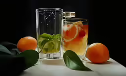 two glasses of water next to oranges on a table