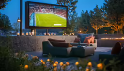 an outdoor cinema area with couches and a tv