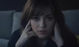 a young woman holding her hand to her face