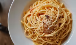 there is spaghetti in the white bowl on the table