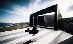 a room with a big white window and black furniture