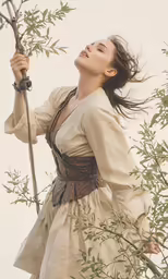a girl dressed as a young woman wearing a white dress holding onto a tree branch