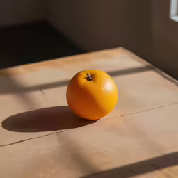 an orange sits in the light on a wooden table