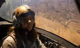 the person is wearing a helmet as she sits in the jet plane