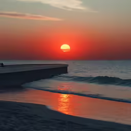 a sunset view from the beach near a concrete wall