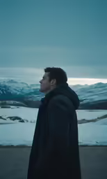 the man standing alone looking out over the snowy mountain valley