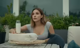 a beautiful young woman sitting at a table in front of a milk bottle