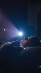 the woman is looking up while lying on her bed