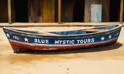 a canoe with blue, white and red paint sitting on a ground
