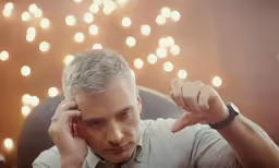 a man sitting in a chair with his hand on his head