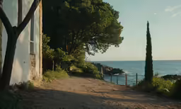 a dirt road passes by an old building and sea