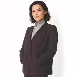 a woman in a dark suit poses with her hands on the hips