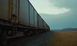 a freight train on the tracks in the grass