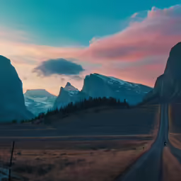 the road is running between two mountains at sunset