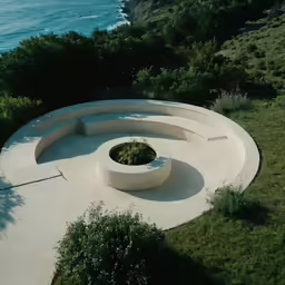 concrete bench sitting on a grassy area overlooking the ocean