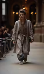 a woman wearing a coat and pants walking down a sidewalk