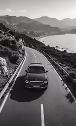 a car driving down a long road by the ocean