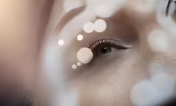 someones face and a make - up is reflected by the lens