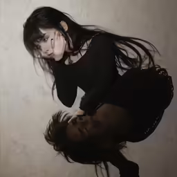 a young woman leaning against the wall and touching her face with the finger