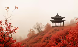 a pagoda on a hill surrounded by trees and red flowers