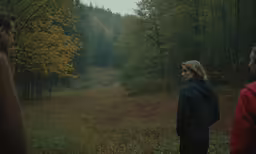 a woman and two men standing in a forest area