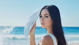 young woman on beach with umbrella in hand