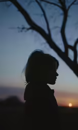 the silhouette of a woman near a tree