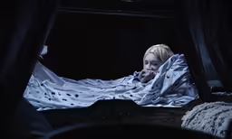 a person under a blanket on a bed