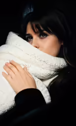 the woman is holding her scarf over her face