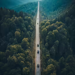an aerial view of cars traveling down a highway in the mountains