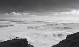 two men standing on a cliff looking at the ocean