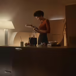 a woman standing in the light in front of a kitchen island