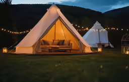 a tippy tent lit up at night in the woods