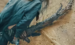 a woman with a gun and a blue jacket