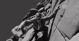man climbing up the side of a large cliff