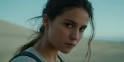a young woman stands with her head turned to the right