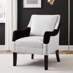 a white chair in front of a black wall and a white rug