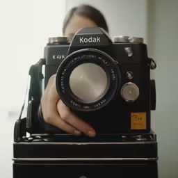 a person holding an old camera in front of a mirror