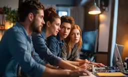 a row of young people sitting at a computer