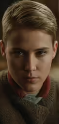 a man with blond hair and blue eyes looks into the camera