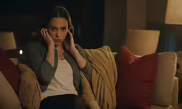 the girl is sitting on the sofa with her hands on her head