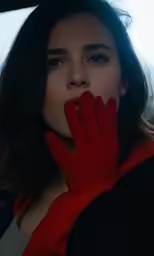 young woman wearing red gloves with hands on cheek