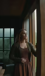 a beautiful young woman dressed in brown posing by the door