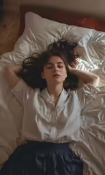 a woman laying on top of a bed with her arms stretched