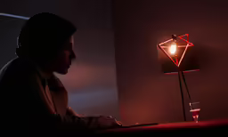 a person with headphones on sitting in front of a lamp