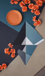 a table with an orange flower and a black plate