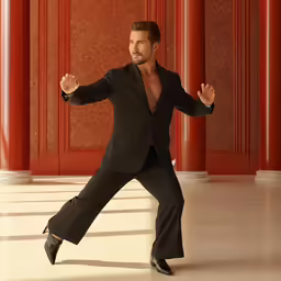 a man in a tuxedo poses in an empty room