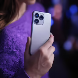 a woman holding an iphone while standing