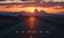 the sun setting behind a city skyline and on top of a road