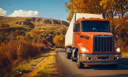 an orange truck is parked on a side road,a semi truck on the road with trees